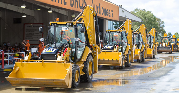 Line up of loader backhoes making their way across the ramp